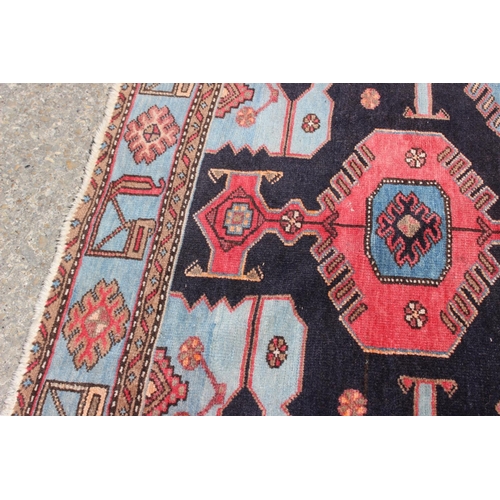 674 - A Caucasian rug with three red medallions on a black ground, and bird and floral border on a light b... 