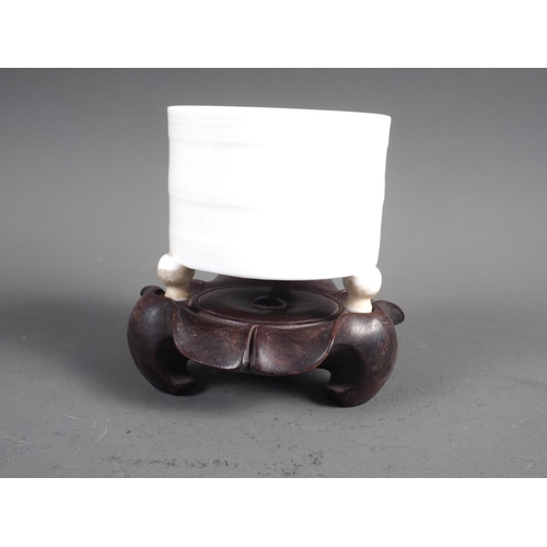 57 - A Chinese blanc-de-chine cylindrical censor on three supports, 2 1/4” high, with carved hardwood sta... 