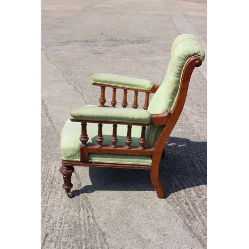 495 - An Edwardian oak showframe armchair, button upholstered in a green patterned fabric, on reeded and c... 