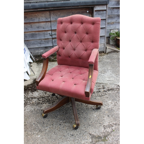 551 - A desk elbow chair, button upholstered in a red fabric, on swivel splay castored support