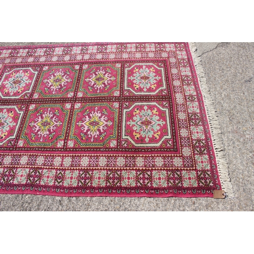 637 - A Moroccan carpet of traditional design with eight central medallions on a pink ground, 61