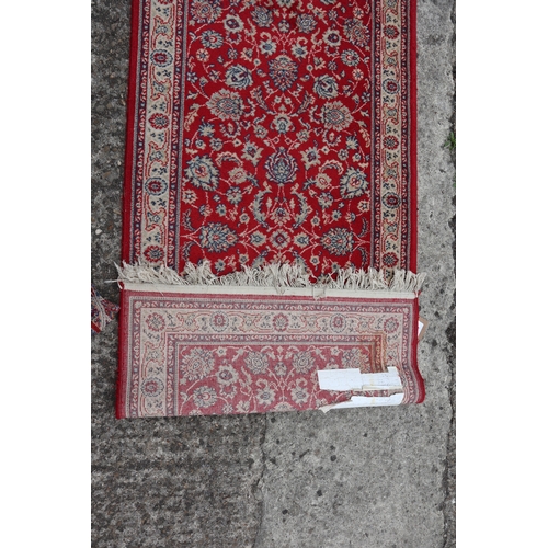 627 - A Persian design runner with central floral design on a red ground and multi-bordered in shades of r... 