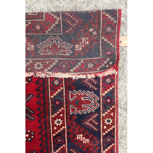 635 - A Caucasian rug with three central tarantulas on a red ground and multi-bordered in shades of blue, ... 