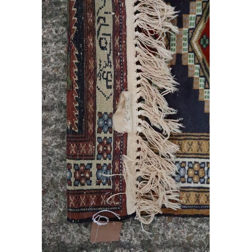 667 - A signed Bokhara mat with two diamond lozenges on a dark blue ground, 25