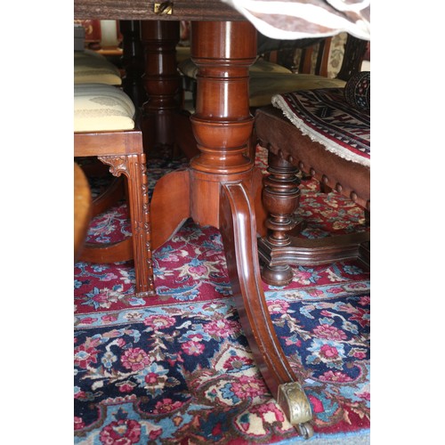 597 - An early 20th century mahogany triple pedestal dining table with two extra leaves, on turned columns... 