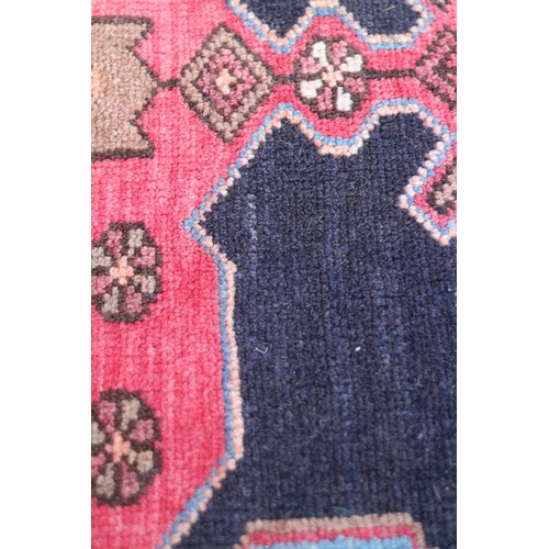 674 - A Caucasian rug with three red medallions on a black ground, and bird and floral border on a light b... 