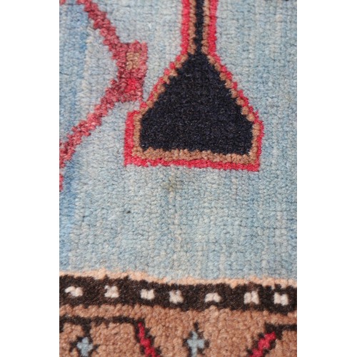 674 - A Caucasian rug with three red medallions on a black ground, and bird and floral border on a light b... 