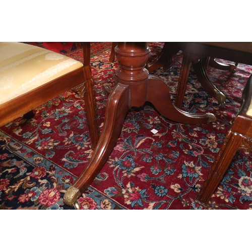 597 - An early 20th century mahogany triple pedestal dining table with two extra leaves, on turned columns... 