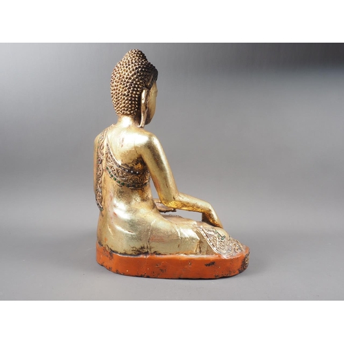 88 - An Oriental carved wood figure of a seated Buddha with gilt and jewelled decoration, 16