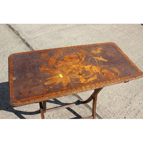 537 - An early 20th century pokerwork folding table, on 'X' frame supports, 30