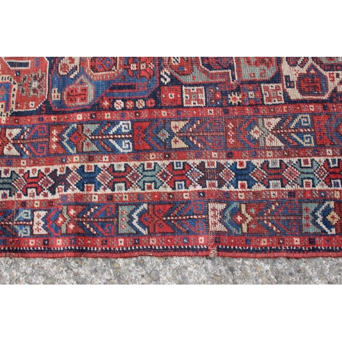 574 - A Caucasian tribal wool rug with stylised cypress tree and geometric designs with multi-guard border... 