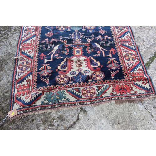 575 - A Hamadan wool rug with three central medallions with geometric and animal designs on a dark blue gr... 