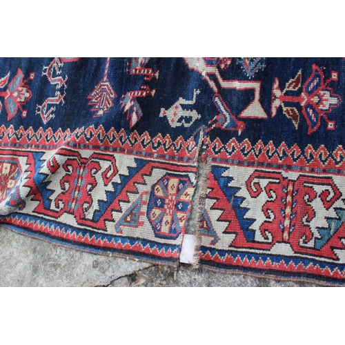 575 - A Hamadan wool rug with three central medallions with geometric and animal designs on a dark blue gr... 