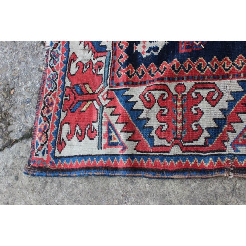 575 - A Hamadan wool rug with three central medallions with geometric and animal designs on a dark blue gr... 