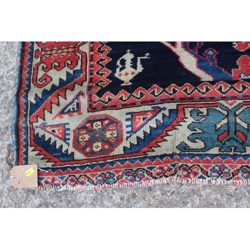 575 - A Hamadan wool rug with three central medallions with geometric and animal designs on a dark blue gr... 