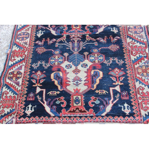 575 - A Hamadan wool rug with three central medallions with geometric and animal designs on a dark blue gr... 