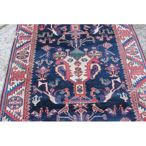 575 - A Hamadan wool rug with three central medallions with geometric and animal designs on a dark blue gr... 