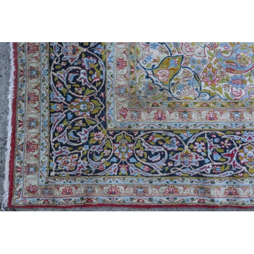 586 - A Kirman carpet with blue central medallion on a red ground with scrolls and flowers, and multi-bord... 