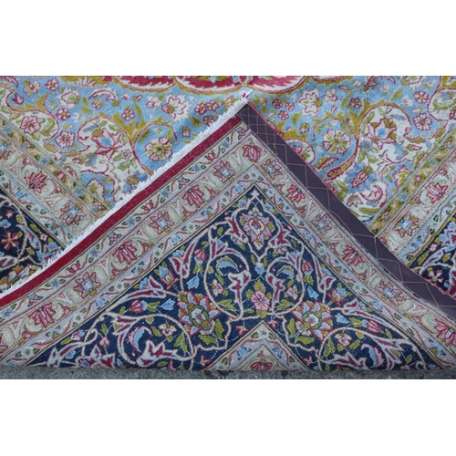 586 - A Kirman carpet with blue central medallion on a red ground with scrolls and flowers, and multi-bord... 