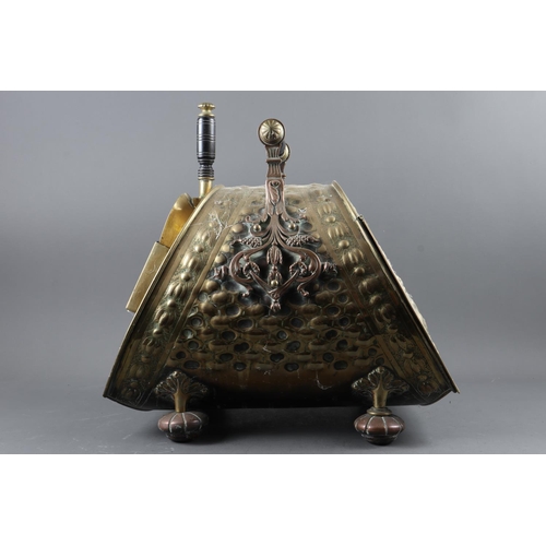 153 - An embossed brass coal scuttle and scoop with ebonised handles