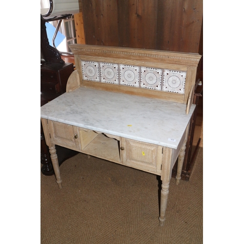 570 - A pine washstand with tile back and marble top over cupboards and recess, on turned supports, 36