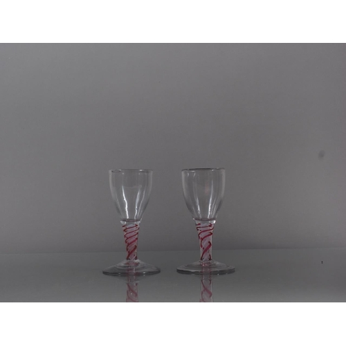 83 - A pair of cordial glasses with red and white cotton twist stems, 4.4