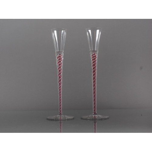 84 - A pair of early 20th century Continental cordial glasses with red and white cotton twist stems, 8.9