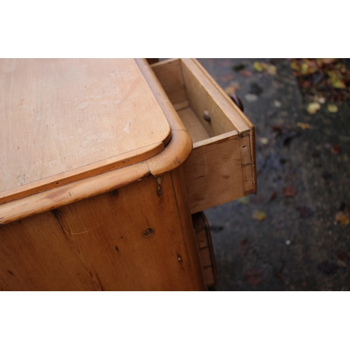 595 - A 19th century waxed pine breakfront desk with central recess, fitted seven drawers, 44