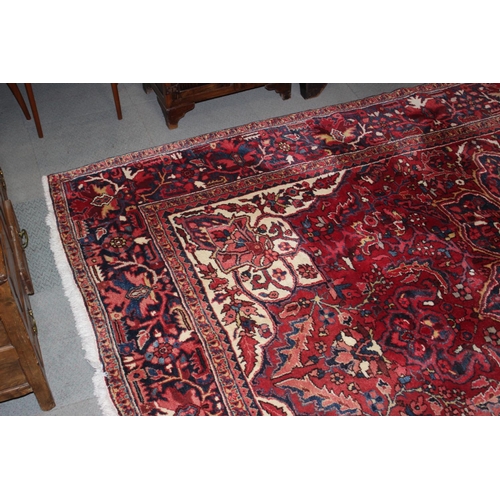 601 - A Persian carpet with floral designs and multi-borders on a red ground in shades of dark blue and na... 