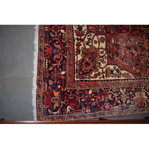 601 - A Persian carpet with floral designs and multi-borders on a red ground in shades of dark blue and na... 