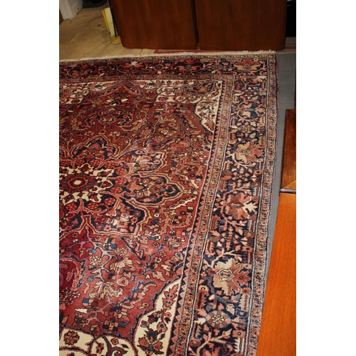 601 - A Persian carpet with floral designs and multi-borders on a red ground in shades of dark blue and na... 