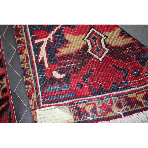 601 - A Persian carpet with floral designs and multi-borders on a red ground in shades of dark blue and na... 