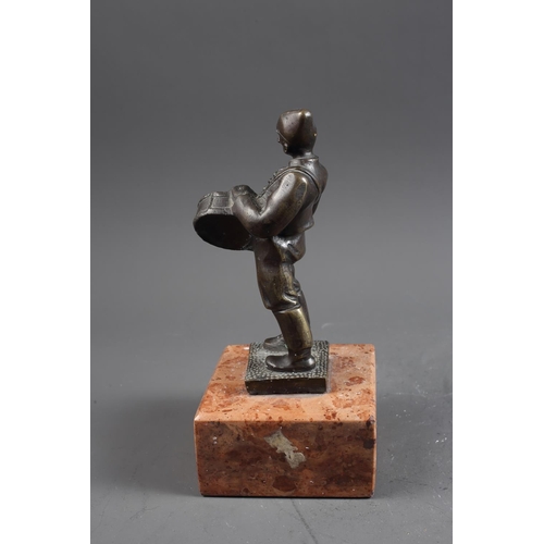 159 - Bokos: a patinated bronze figure of a drummer, on pink marble base, 10