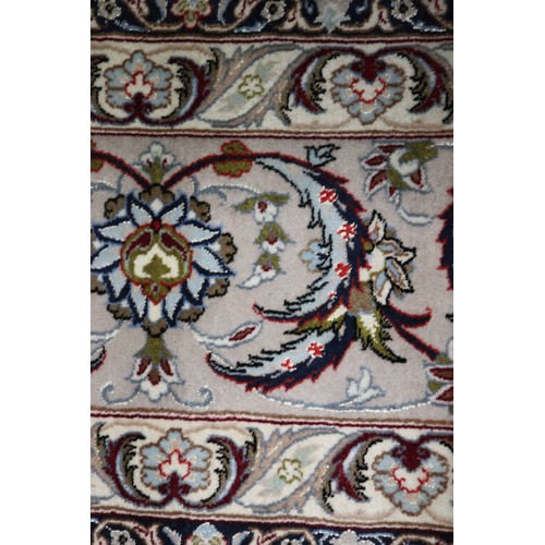 603 - A Persian Isfahan signed carpet of traditional design with all-over scrolls and leaves in shades of ... 