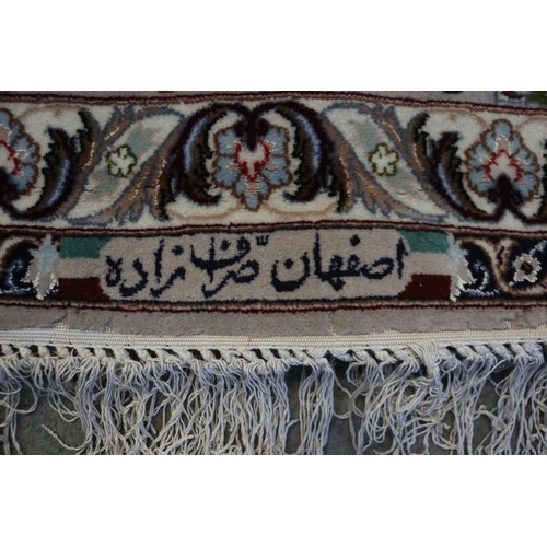 603 - A Persian Isfahan signed carpet of traditional design with all-over scrolls and leaves in shades of ... 