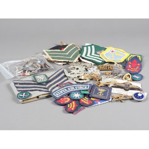 204 - A quantity of military cap badges, patches, buttons and other similar items, some mounted