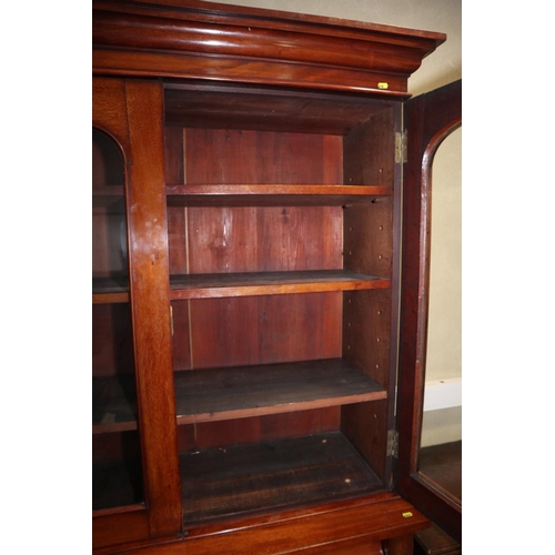 443 - A Victorian mahogany bookcase, the upper section enclosed two glazed doors over drawer and cupboards... 