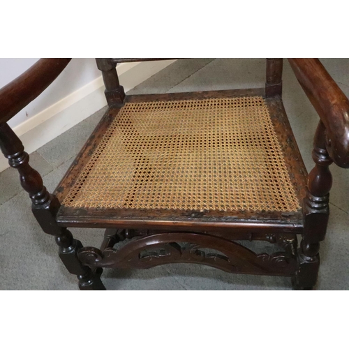 463 - A late 17th century carved oak open armchair with padded back and cane seat, and loose seat cushion,... 