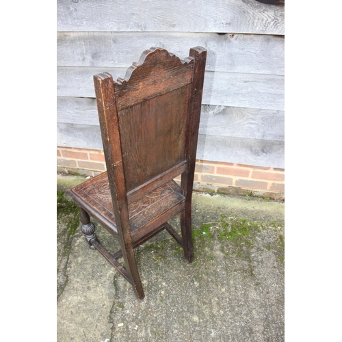 561 - A 17th century style carved oak hall chair with panel seat, on turned and stretchered supports