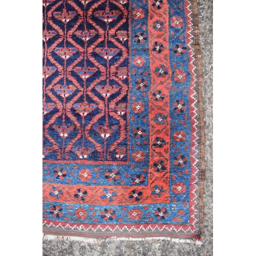 572 - A Baluchi rug with all-over lattice and flower design in shades of red, brown and natural on a dark ... 