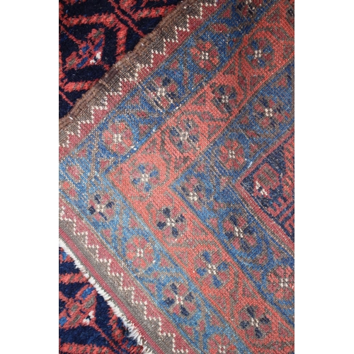 572 - A Baluchi rug with all-over lattice and flower design in shades of red, brown and natural on a dark ... 