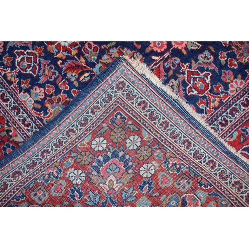 574 - A Kashan rug with red central medallion and all-over floral design on a blue ground, multi-bordered ... 