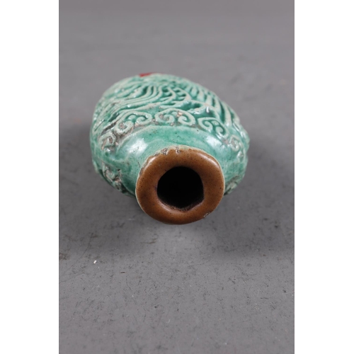 105 - A Chinese green glazed ceramic relief dragon decorated snuff bottle, 2 3/4