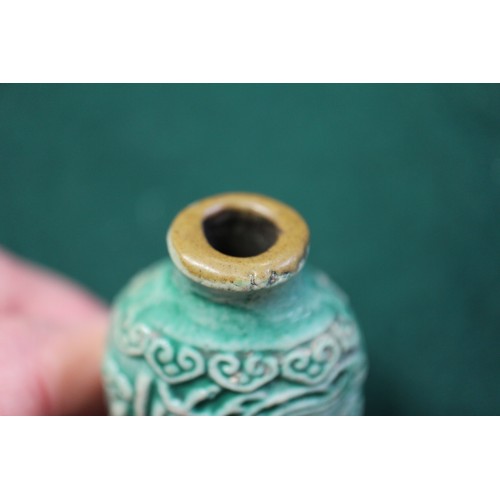 105 - A Chinese green glazed ceramic relief dragon decorated snuff bottle, 2 3/4