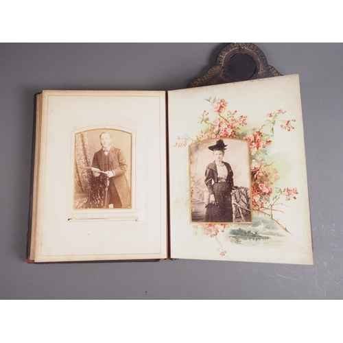 221 - A Victorian photograph album on strut with glazed apertures to cover and pediment, containing a quan... 