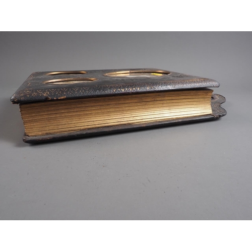 221 - A Victorian photograph album on strut with glazed apertures to cover and pediment, containing a quan... 