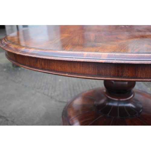 497 - An early 19th century rosewood circular tilt top dining table, on faceted bulbous column and lion pa... 