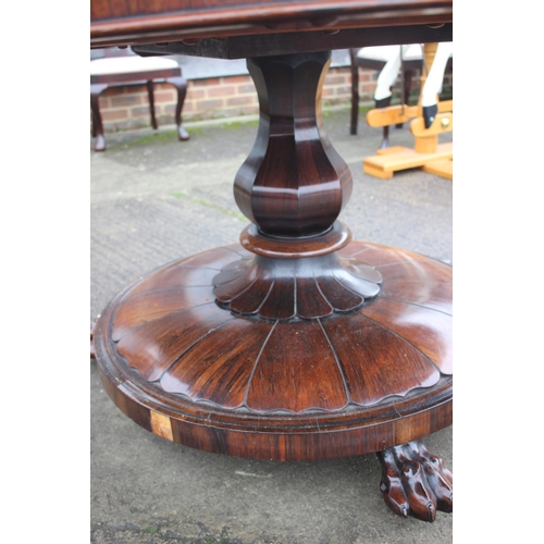 497 - An early 19th century rosewood circular tilt top dining table, on faceted bulbous column and lion pa... 