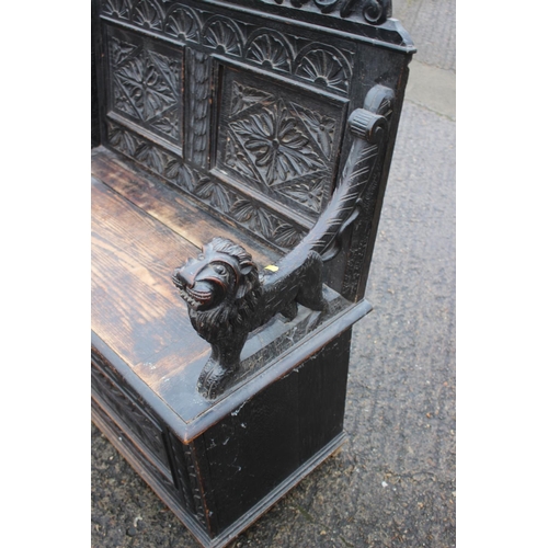 501 - A late Victorian carved oak box seat settle with lion terminal arms, on stile supports, 42