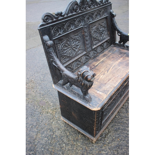 501 - A late Victorian carved oak box seat settle with lion terminal arms, on stile supports, 42